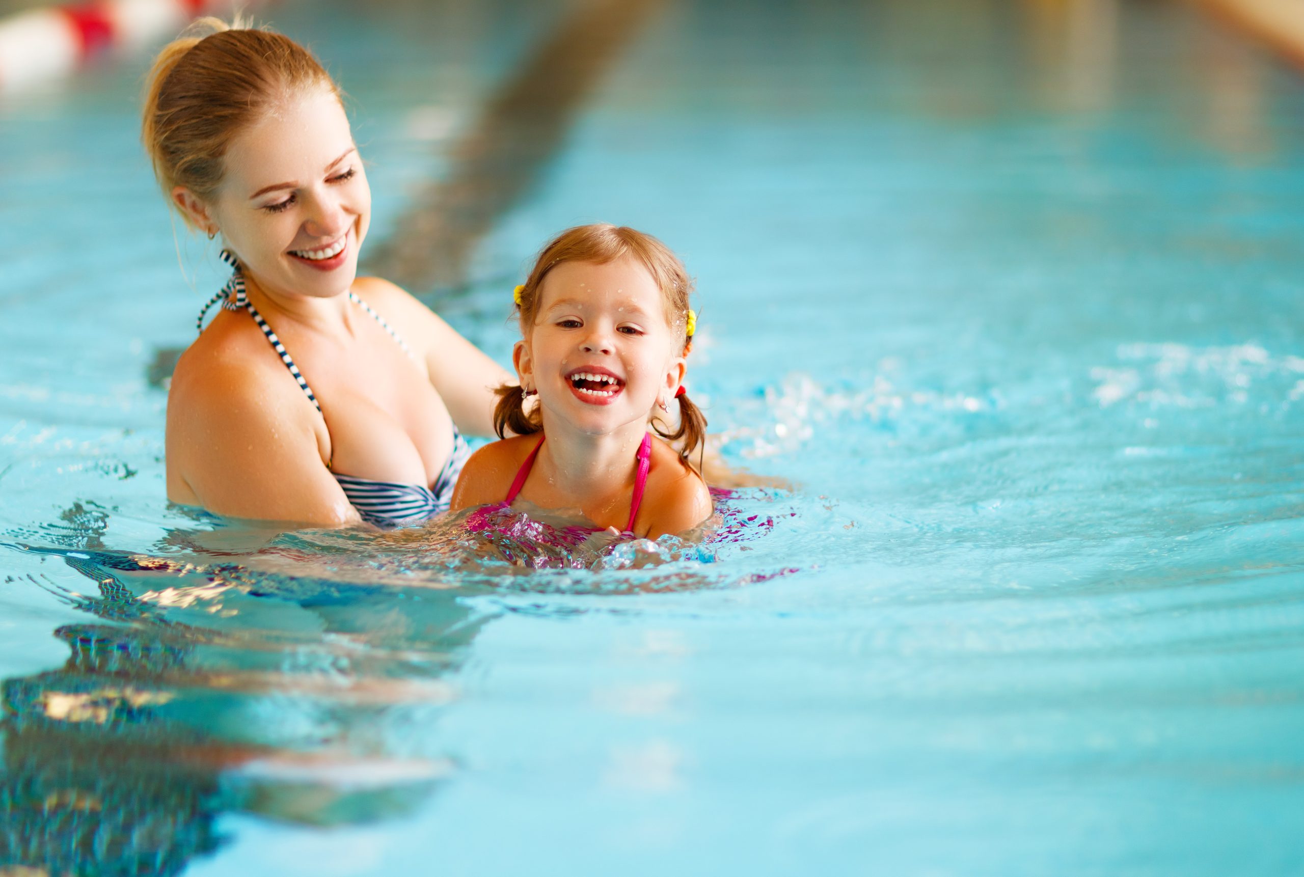 Mother teaches child to swim in pool